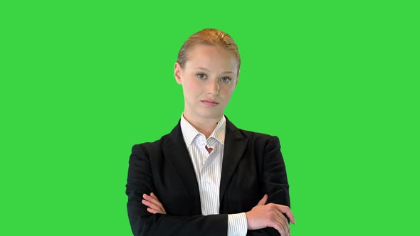 Young Smiling Female Standing with Folded Hands on a Green Screen Chroma Key