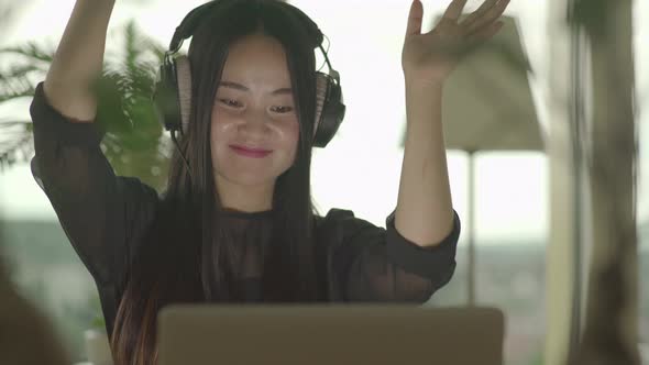 Happy Asian Woman Watching Music Video on Computer