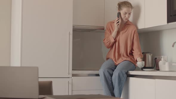 Young Woman Chatting on Phone at Kitchen Table