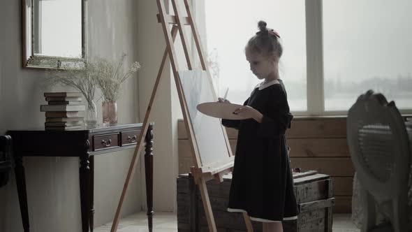 Little girl artist painting with paintbrush