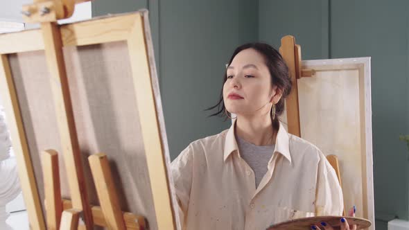 A Woman Artist in a Paintstained Shirt Drawing on Canvas