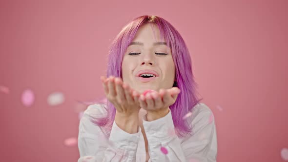 Young Woman Blows Off Bright Confetti From Hands Closeup