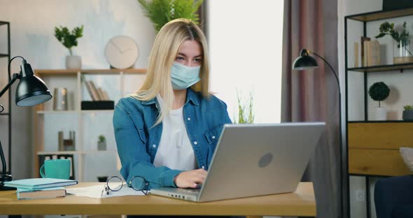 Female Worker in Facial Mask Working on Computer in Home Office