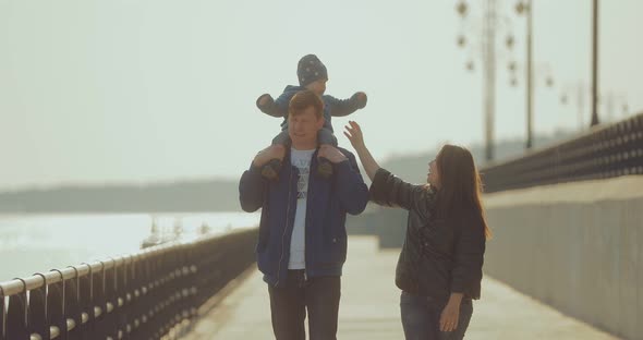 Korean Woman Walks with Her Husband and Little Son on the Embankment in the Spring