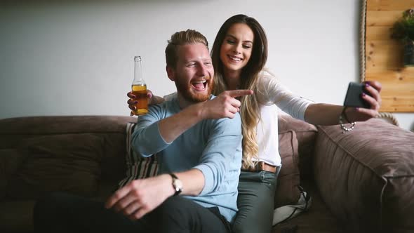 Young Couple in Apartment Looking at Smart Phone and Smiling