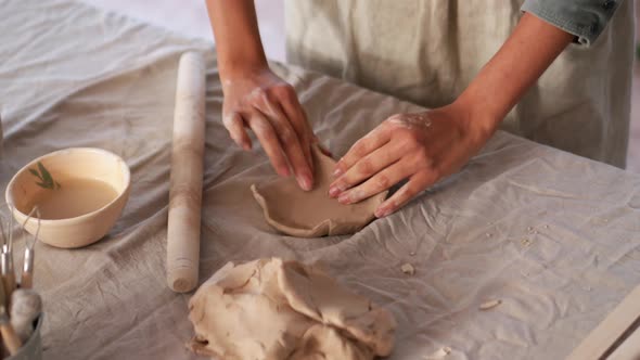 Female hands sculpting plate of clay