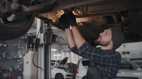 Auto Mechanic Fixing Problem on Undercarriage of Car