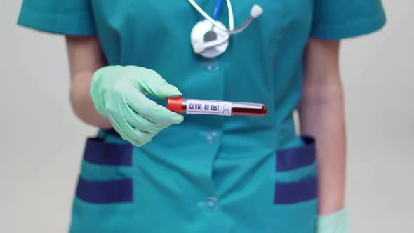 Medical Doctor Nurse Woman Wearing Protective Mask and Latex Gloves - Holding Blood Test Tube