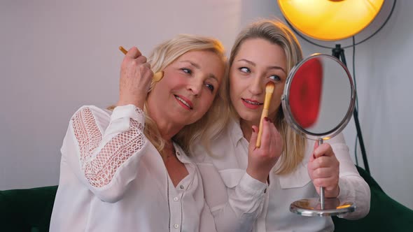 Indoor Shot in an Apartment of Two Confident Attractive Middleaged Women Doing Makeup Preparing for