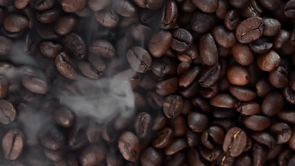 Close up of seeds of coffee. Fragrant coffee beans are roasted smoke comes from coffee beans.