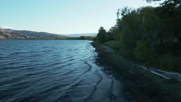 Low flying aerial shot over a deep blue Clutha river in Otago Region, New Zealand. Wide blue river w