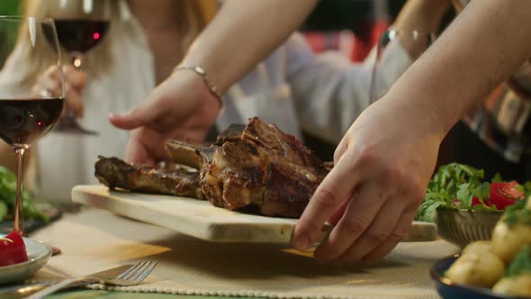 Man Puts a Plate of Meat on the Table