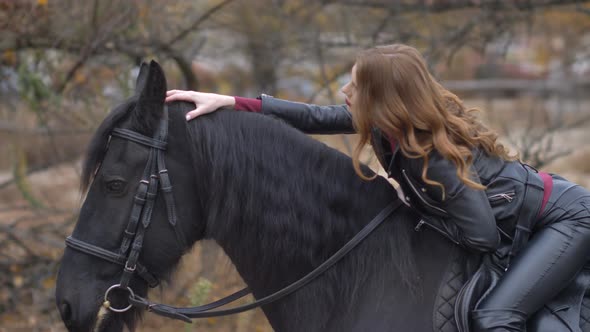 Beautiful Young Woman Sitting Astride Hugs a Horse and Posing Outdoors