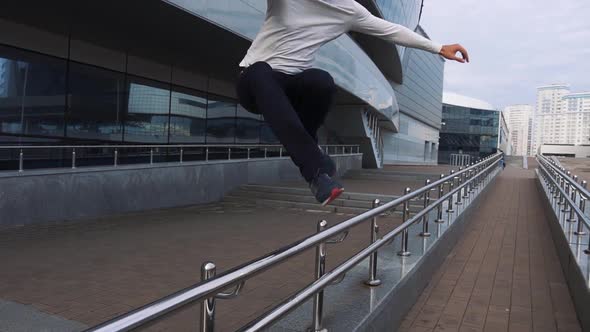 Young freerunner perfoming parkour exercises using railings.