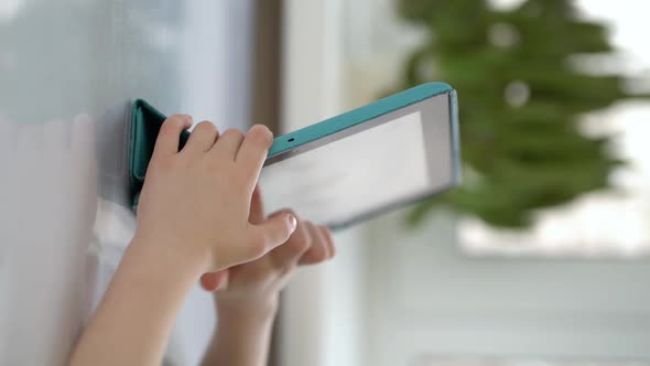 Preschooler Sits at a Table and Looks at a Digital Tablet