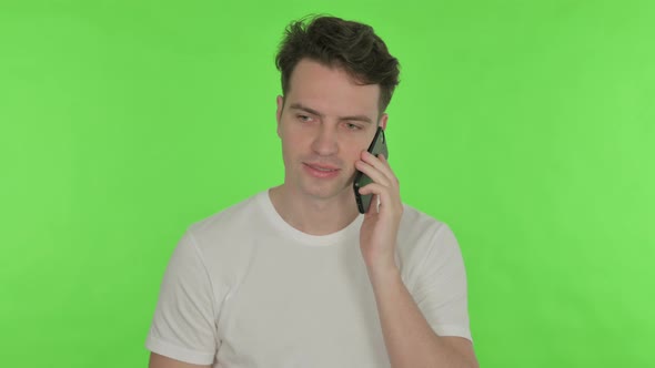 Young Man Talking on Phone on Green Background