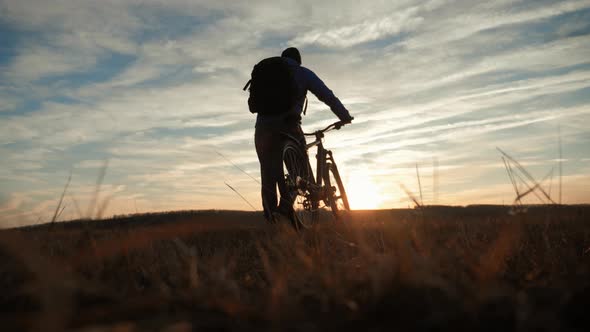 Silhouette Cyclist Man on a Mountain at Sunset.