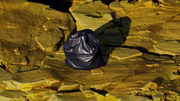 Black Trash Bag Lay on a Rocky Beach