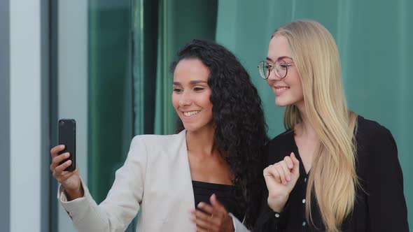 Confident Diverse Businesswomen Chatting with Colleague Using Smartphone Outdoors Smiling