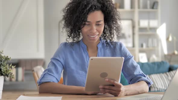 African Woman Celebrating Success on Tablet