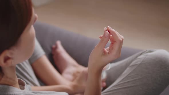 Woman Taking Antiviral Pills and Drinking Water