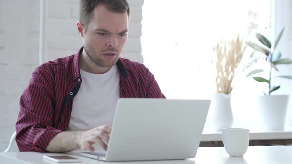 Young Man in Shock While Working on Laptop