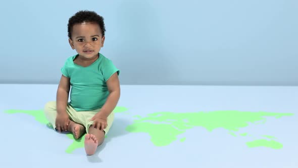 Baby boy sitting on world map on floor