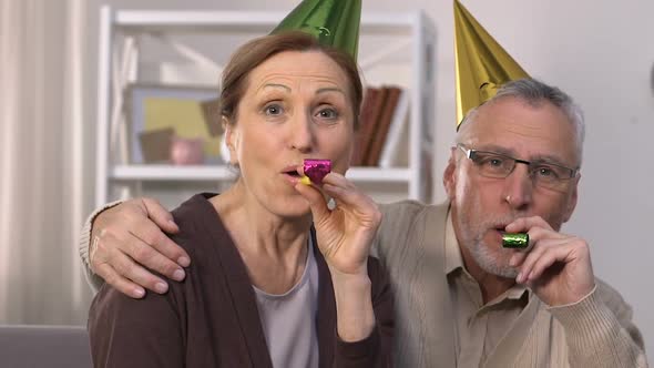Cheerful Senior Couple in Party Hats Celebrating Birthday, Making Surprise