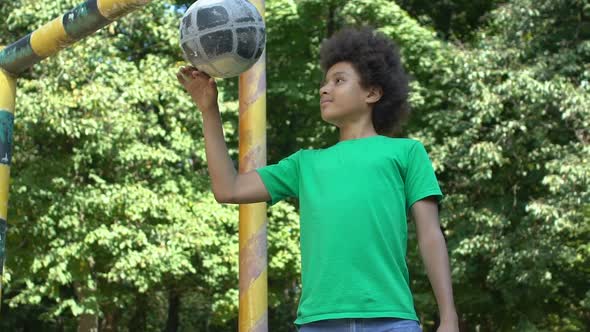 Smiling Black School Pupil Playing Ball Standing Stadium Gate, Sport Activity