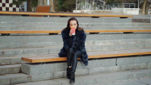 Beautiful woman in park. View of attractive young woman in elegant coat in park