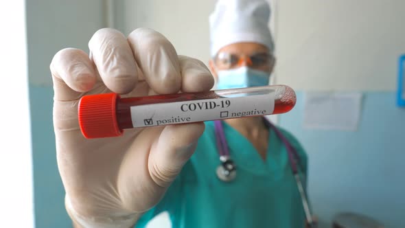 Young Doctor Showing Test Tube with Blood Sample To Coronavirus COVID-19. Medic with Protective