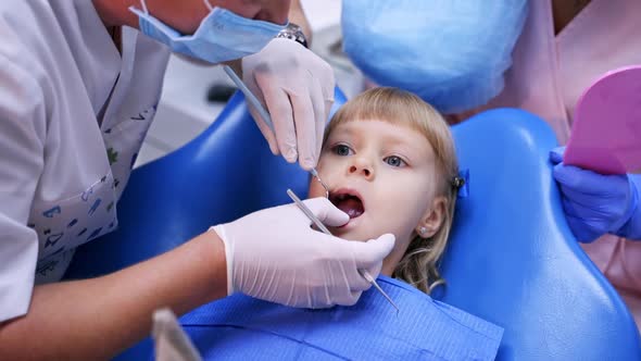 Young girl in dental surgery. Dentist performing dental procedure to girl in clinic