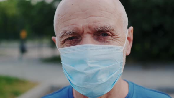 Close Up Portrait of Handsome Old Male Doctor Wearing Medical Face Mask Outdoors