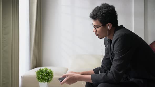 Casual asian young man remove the earphone from his smartphone