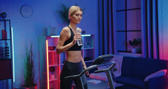 Woman in Sportswear Drinking Water from Bottle while Doing Stepping Exercises on Treadmill