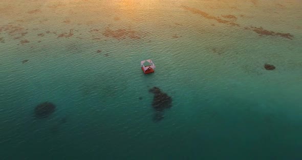 Aerial drone view of a man and woman having dinner on a floating raft boat at sunset