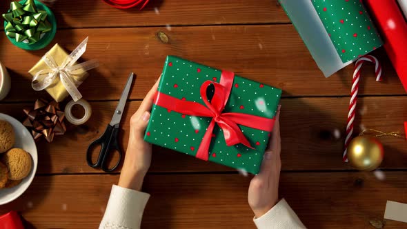 Woman Packing Christmas Gifts at Home Over Snow