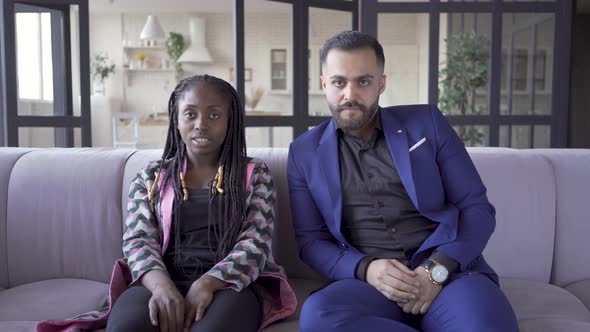 Cute Multiracial Couple Sitting on the Sofa at Home Watching Horror Movie