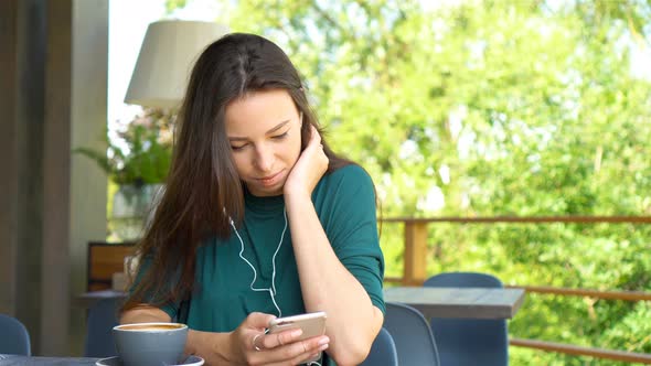 Young Woman with Cell Telephone While Sitting Alone in Coffee Shop During Warm Day. Attractive