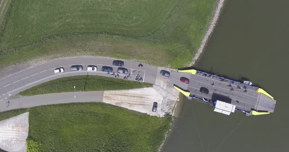 A topdown drone shot of a ferry, loading off cars en people from a river to land, tripod shot, in th