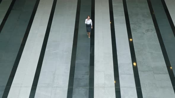 Attractive female leader walks through large empty lobby of a business center