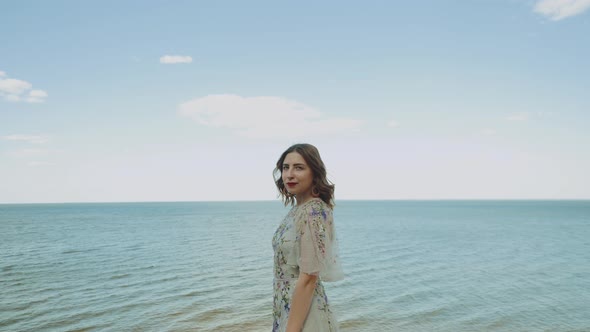 Closeup of Attractive Woman with Red Lips Touches Her Curly Hair Looking at Camera Blue Sea with