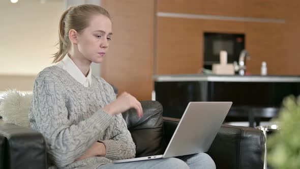 Young Woman Thinking and Working on Laptop at Home 