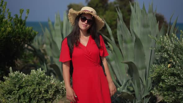 Beautiful Young Caucasian Woman in Red Dress and Sunglasses Posing at Background of Beautiful Cyprus