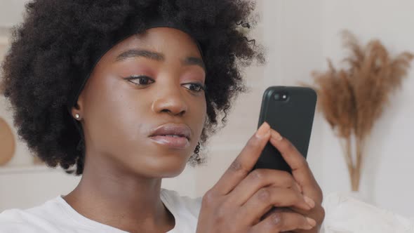 African American Woman Watching Funny Photo or Video on Smartphone at Home