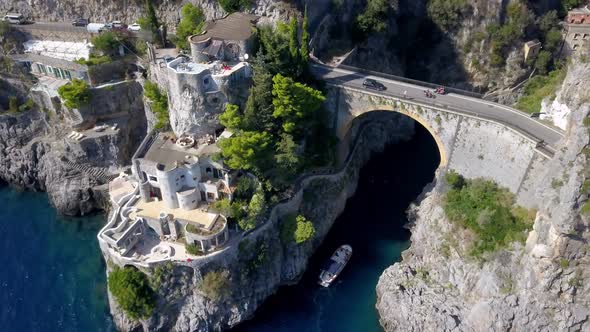 Fiordo di Furore arch bridge in the Italian Almalfi coast with car traffic above and boat entering b