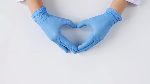 Doctor's Hands in Medical Gloves Shows the Symbol of the Heart on White Background with Copy Space