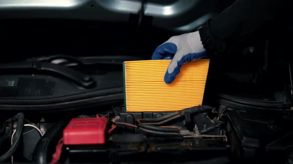 Mechanic in a service station changes the car's air filter as part of warranty service