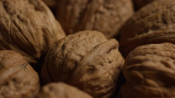 Cinematic, rotating shot of walnuts in their shells on a white surface - WALNUTS