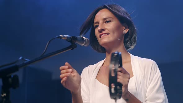 Female Singer with Tambourine and Musician Playing Guitar Performing on Stage